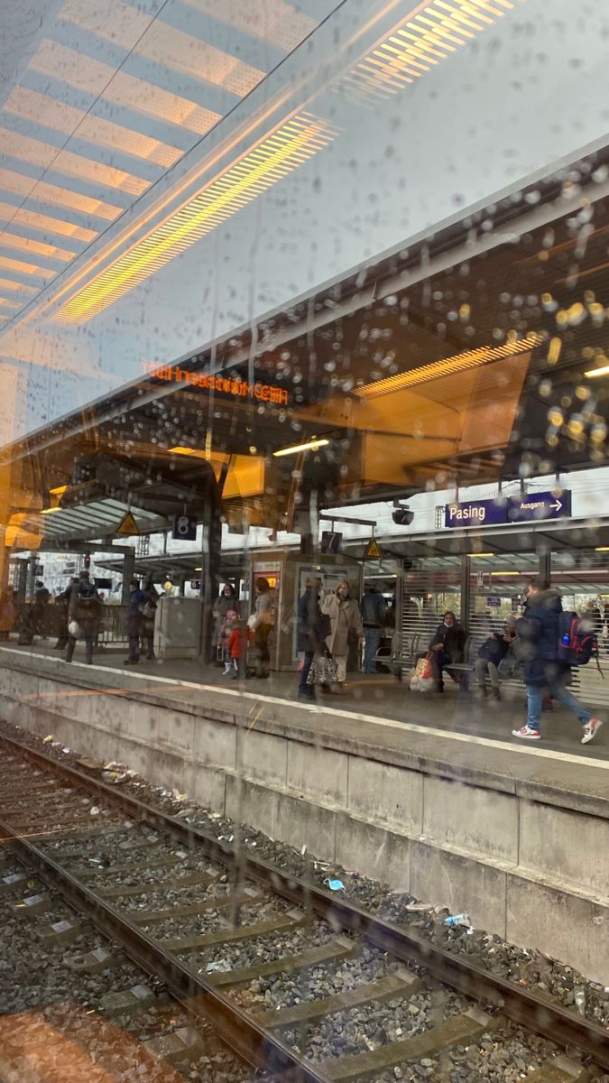 people are waiting at the train station in the rain