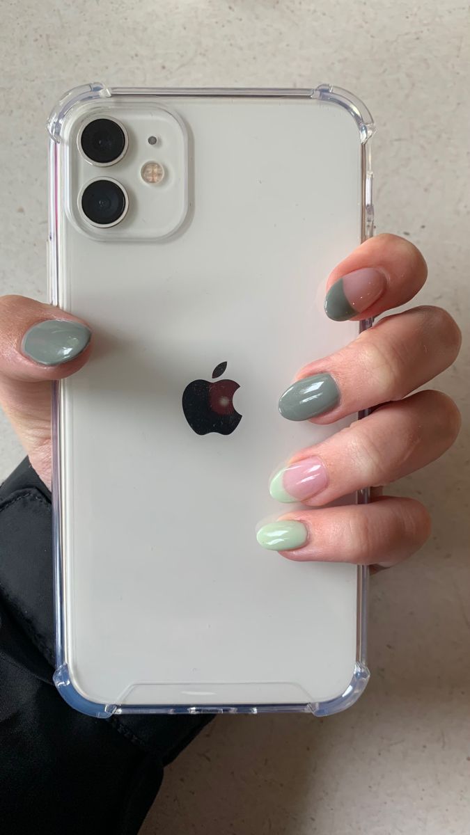 a woman's hand holding an iphone case with green and white nail polish on it