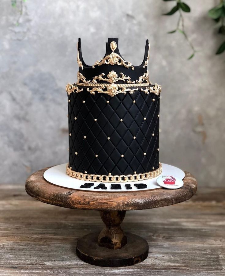 a black and gold decorated cake sitting on top of a wooden table