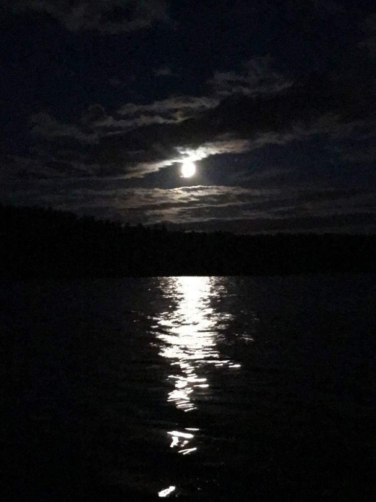 the moon is shining brightly in the dark night sky over the water's surface