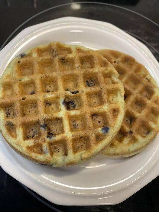 two waffles on a white plate sitting on a black counter top next to each other