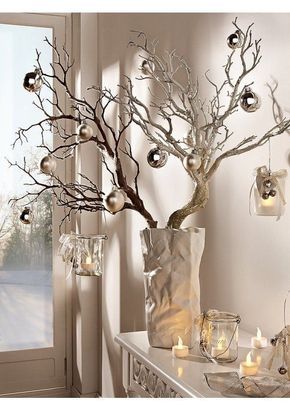 a christmas tree with ornaments and candles in front of a window, next to a glass vase