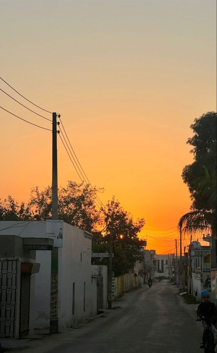 the sun is setting over an alley way with buildings and palm trees on both sides