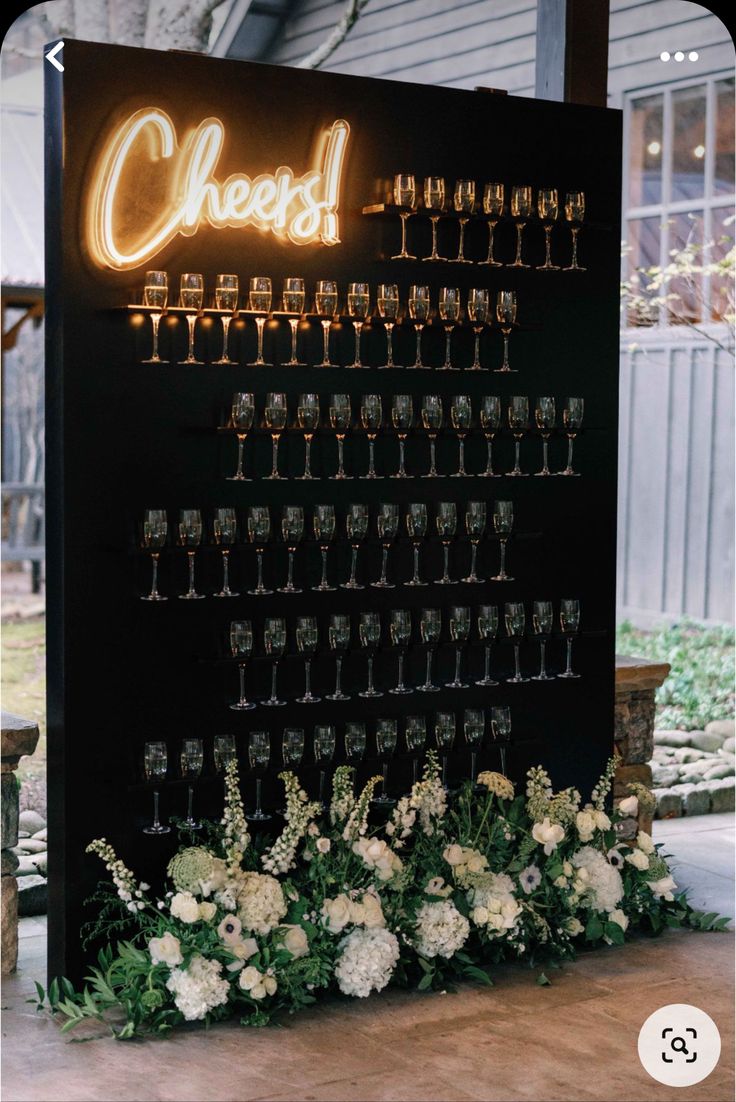 a sign that has some wine glasses on it with flowers in front of it and the words cheese written above it