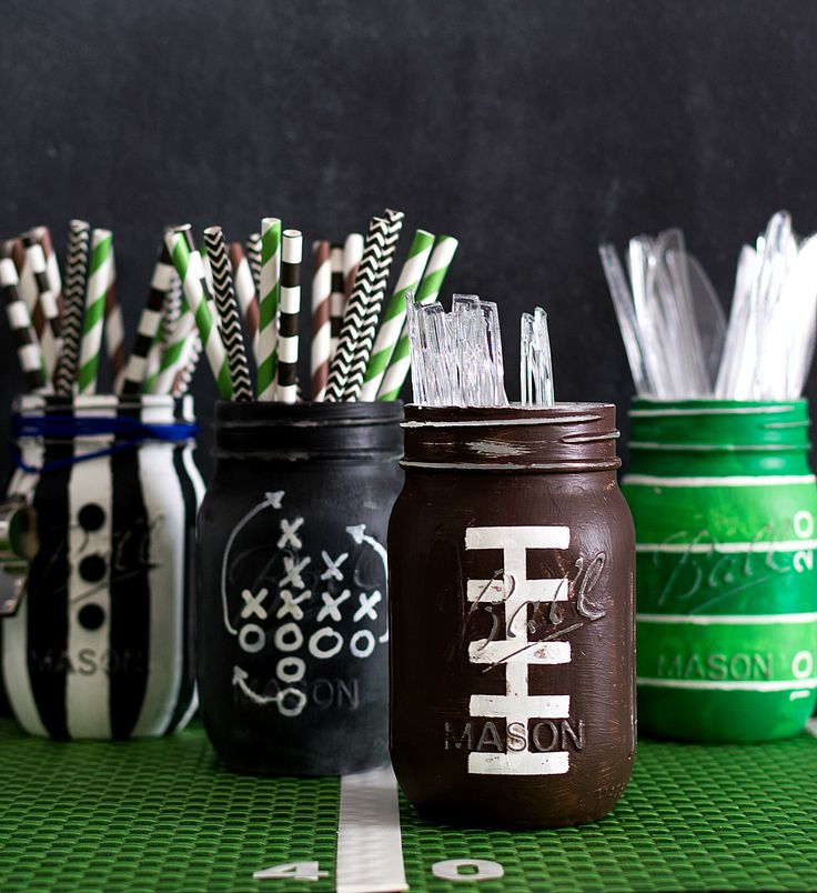 four mason jars filled with drinking straws on top of a green tableclothed surface