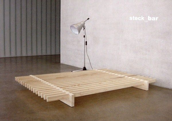 a bed frame with a lamp on top of it in front of a white wall