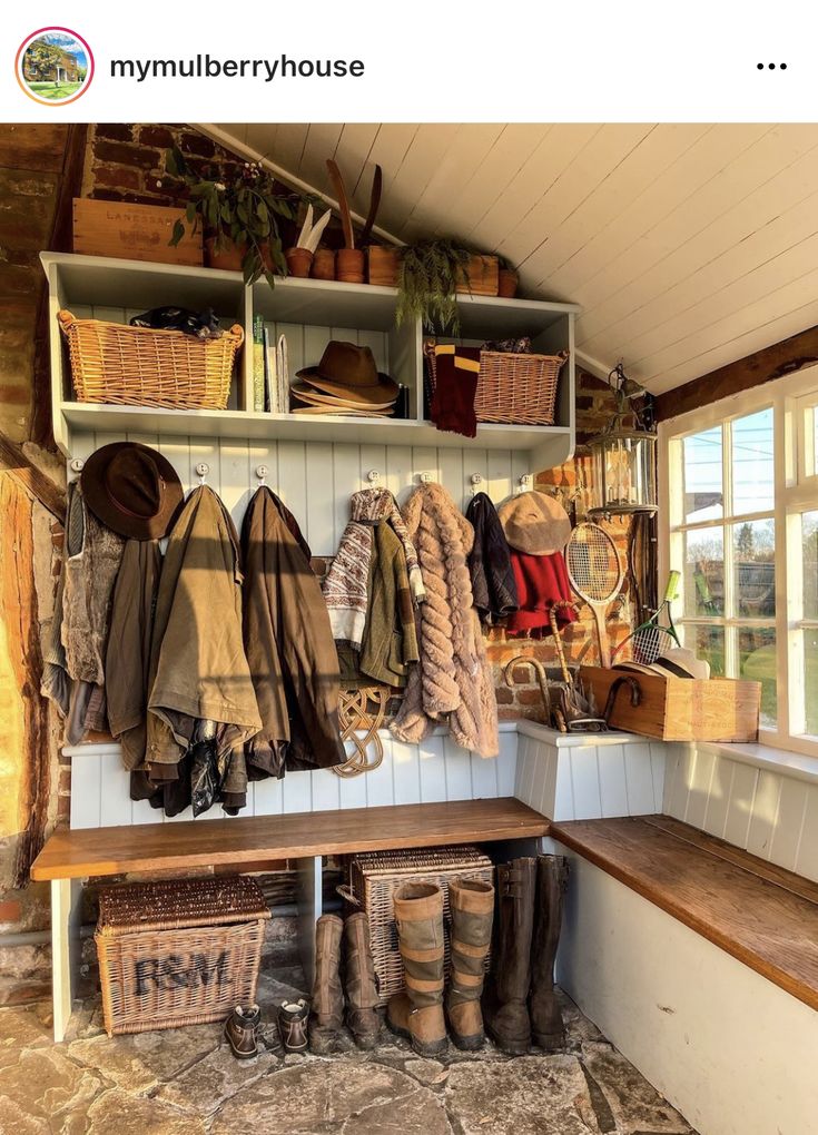 a wooden bench sitting under a window next to a shelf filled with hats and scarves