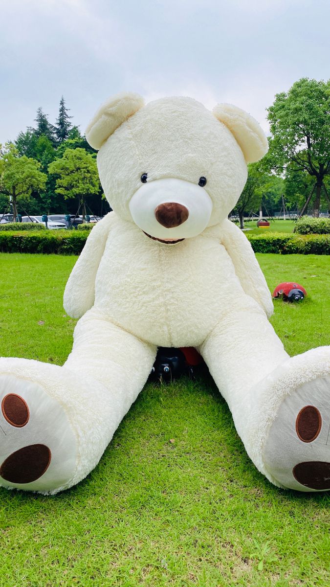 a large white teddy bear sitting in the grass