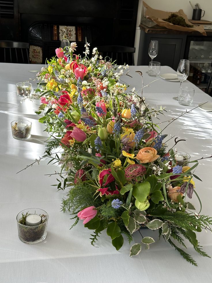 a vase filled with lots of flowers sitting on top of a table next to candles