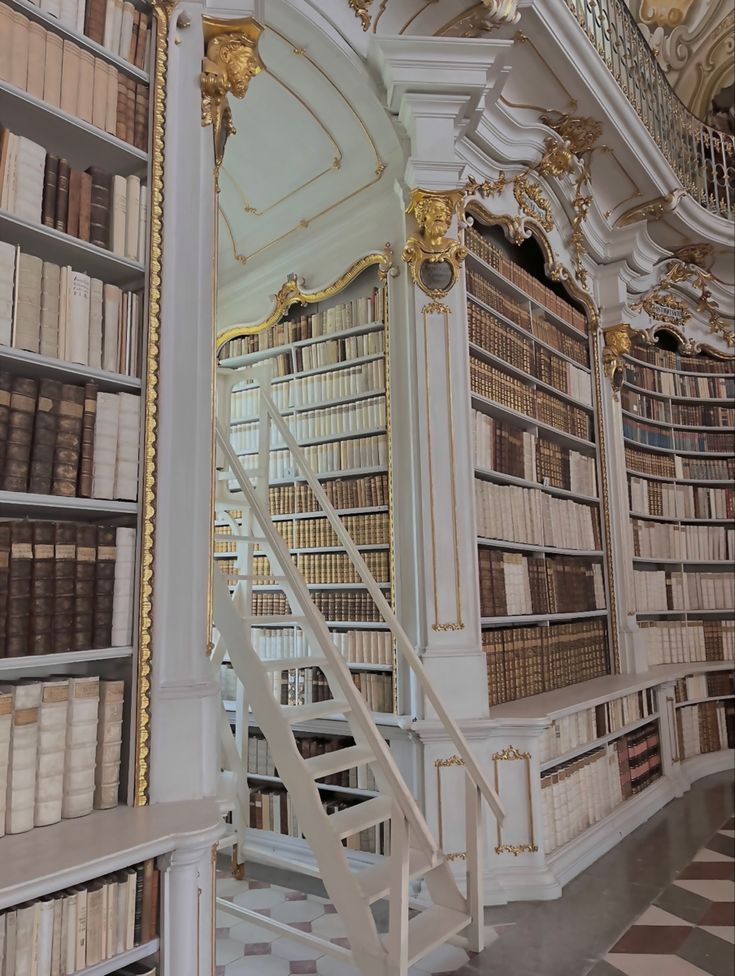 an ornate library with many bookshelves and white staircase leading up to the second floor