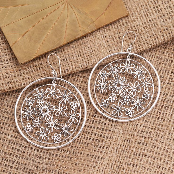 Concentric circles on silver ear wires contain dozens of sterling silver flower blossoms of various sizes and shapes in this pair of earrings from Indonesia's Candradewi. The artist who hails from Celuk--a Balinese village renowned for its gold and silver jewelry--uses silver wire to craft each petal. Hypoallergenic Sterling Silver Flower Earrings, Silver Metal Flower Hoop Earrings, Silver Flower-shaped Metal Hoop Earrings, Hypoallergenic Silver Round Flower Earrings, Hypoallergenic Round Silver Flower Earrings, Hypoallergenic Silver Flower Earrings, Silver Sterling Flower Earrings, Silver Sterling Silver Round Flower Earrings, Bohemian Sterling Silver Pierced Flower Earrings