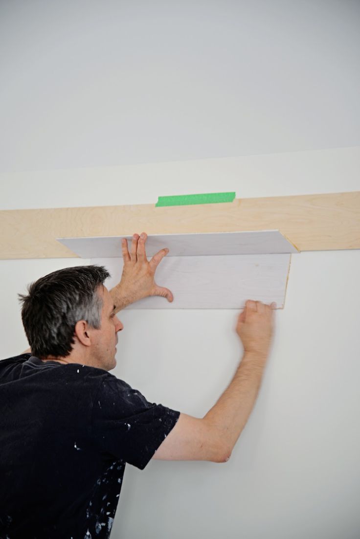 a man is working on the ceiling in his room with wood planks attached to it