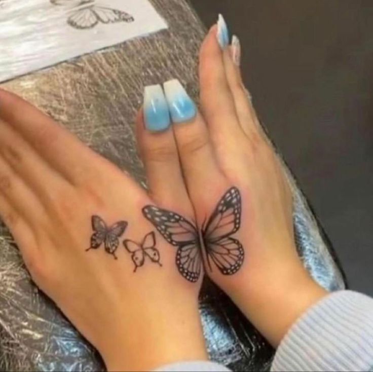 two hands with butterfly tattoos on them