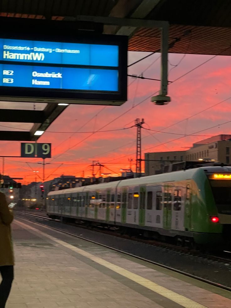 a train is pulling into the station at sunset