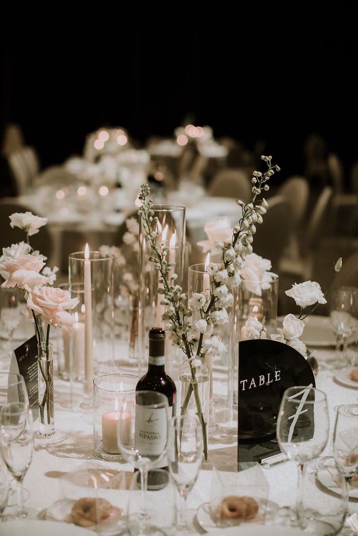 the table is set with candles, wine bottles and flowers