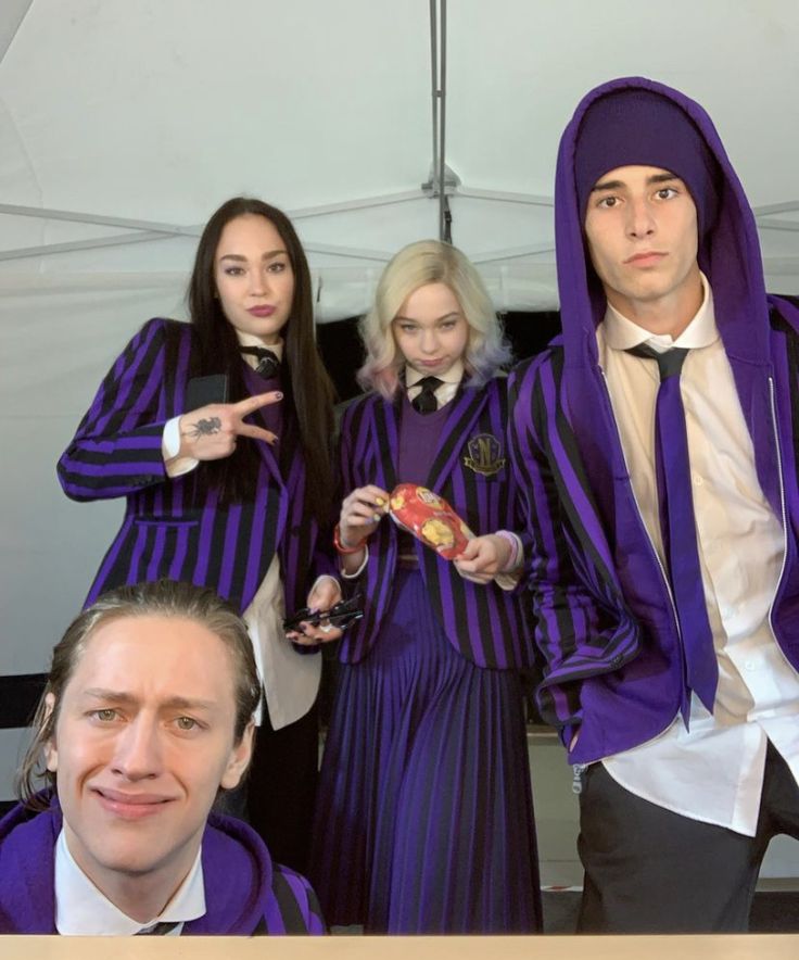 three people dressed in purple and black posing for a photo with one person pointing at the camera