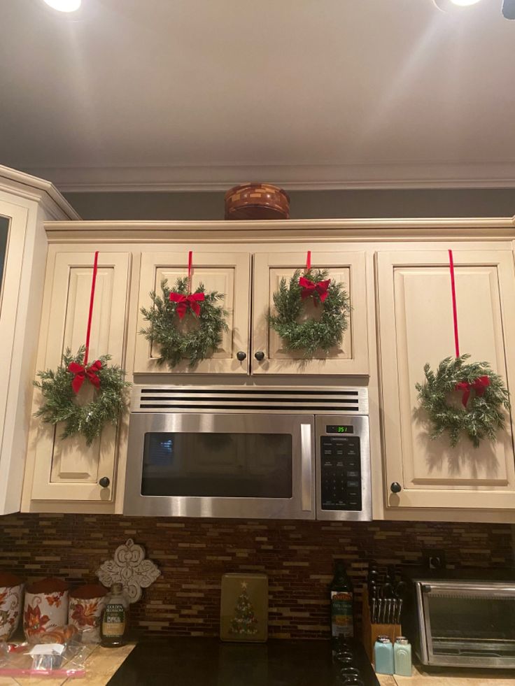 christmas wreaths are hung on the kitchen cabinets above the microwave and stove top oven