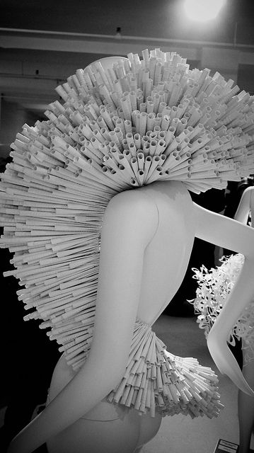 two mannequins are dressed in white paper and one is holding a large fan