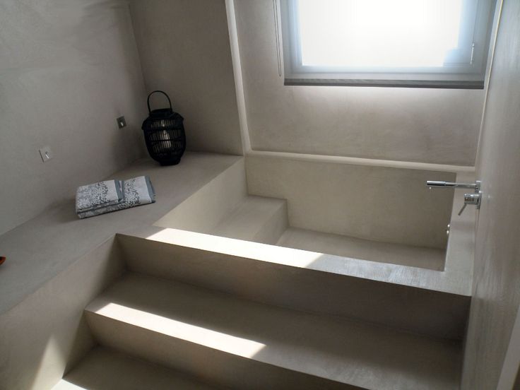 an empty bathtub sitting in the corner of a room with stairs leading up to it