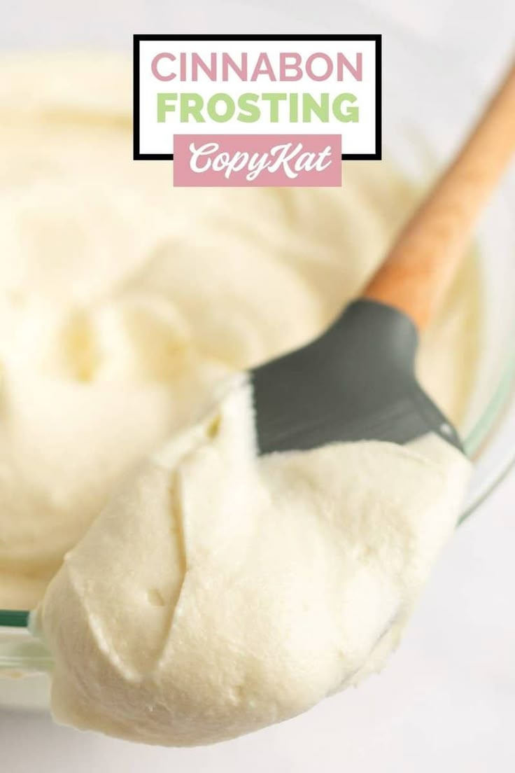 a spoon in a glass bowl filled with whipped cream next to a wooden spatula