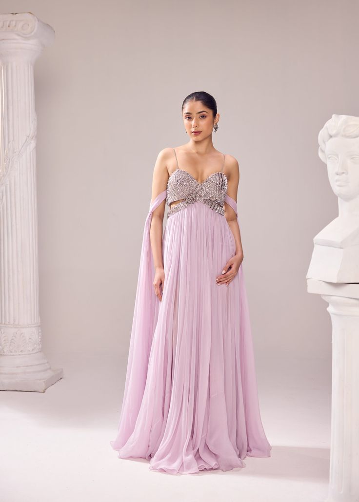 The Clara gown is a true amalgamation of fine couture craftsmanship as the bodice is meticolously embroidered with detailed aari work. The 'infinity flair' of the gown is the key element. The linning has shorts which adds a little more drama to the entire look. Colour: Lilac Material: Italian- Gown No of components: 1 Surface Ornamentation: Hand Embroidery Care Instructions: Dry Clean Shipping Time: 3-4 weeks Gala Gown With Fitted Bodice And Cape Sleeves, Couture Gown With Sheer Bodice For Gala, Couture Ball Gown With Fitted Bodice, Elegant Long Train Festive Dresses, Elegant Festive Dress With Long Train, Fitted Embellished Dress With Cape Sleeves, Couture Gown With Fitted Bodice, Luxury Wedding Gown With Lined Bodice, Luxury Festive Gown With Fitted Bodice