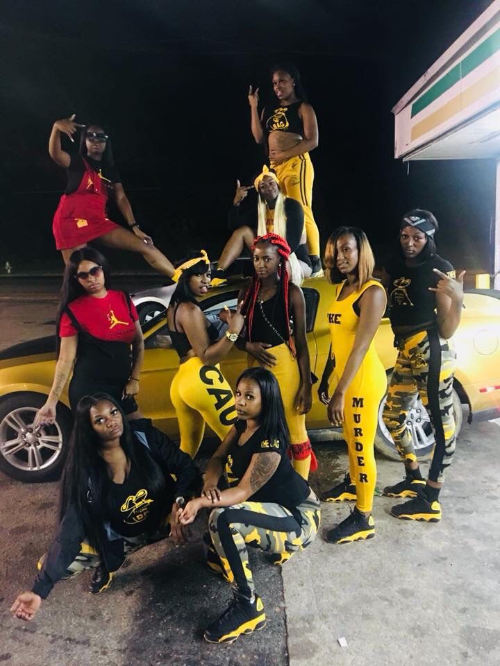 a group of young people standing next to each other in front of a yellow car