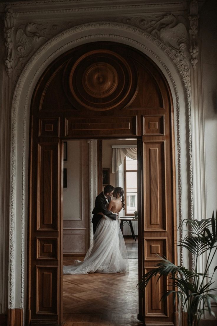 a bride and groom kissing in an ornate doorway