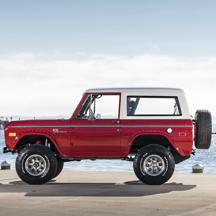 a red truck parked next to the ocean