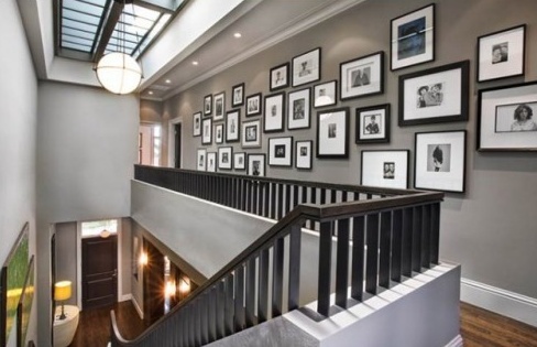 the stairs in this house are decorated with pictures on the wall and below them is a white chair