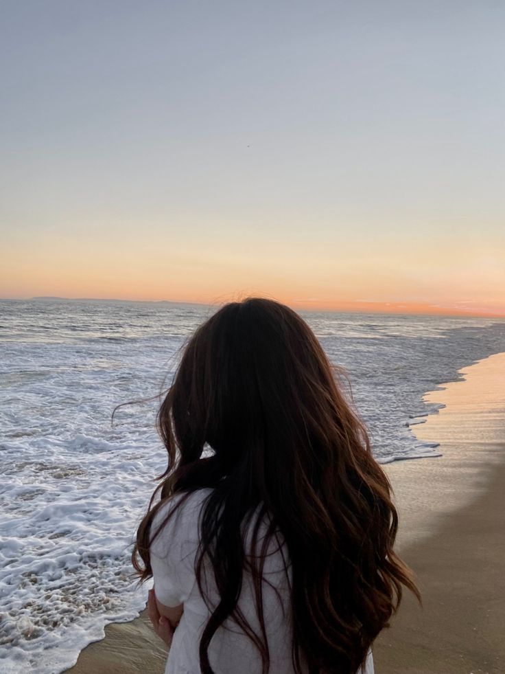 a woman standing on top of a beach next to the ocean