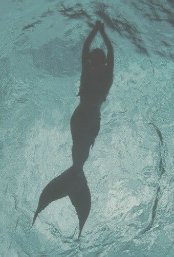 a woman is swimming in the water with her arms above her head and hands behind her back