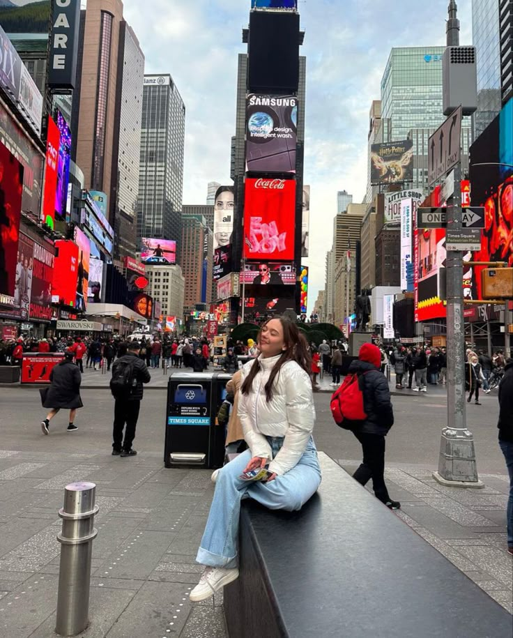 a woman sitting on top of a bench in the middle of a city