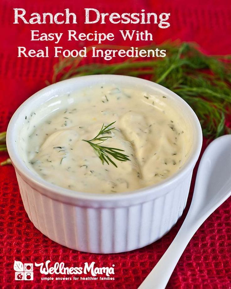 a white bowl filled with ranch dressing on top of a red cloth next to a spoon