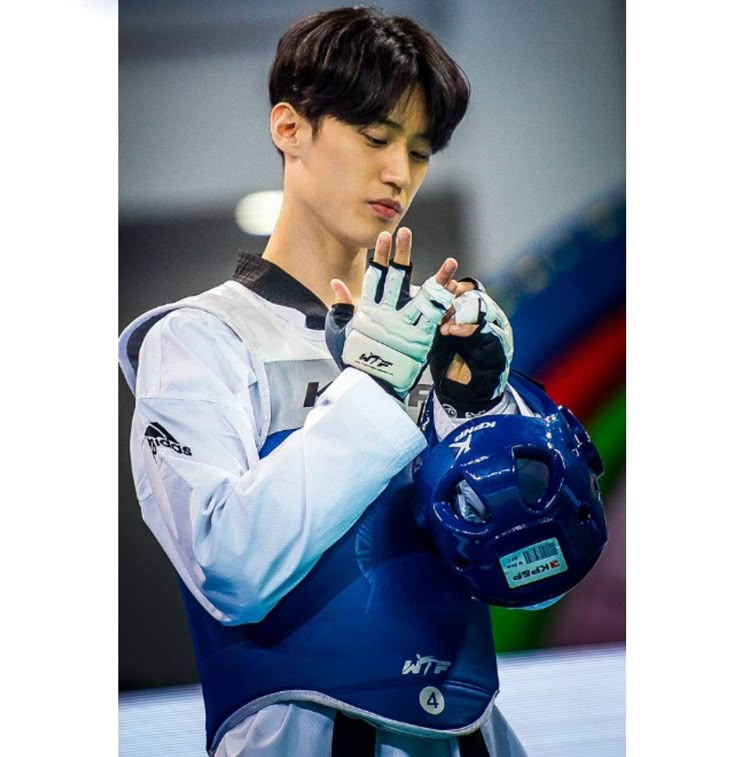 a young man holding a blue helmet and glove