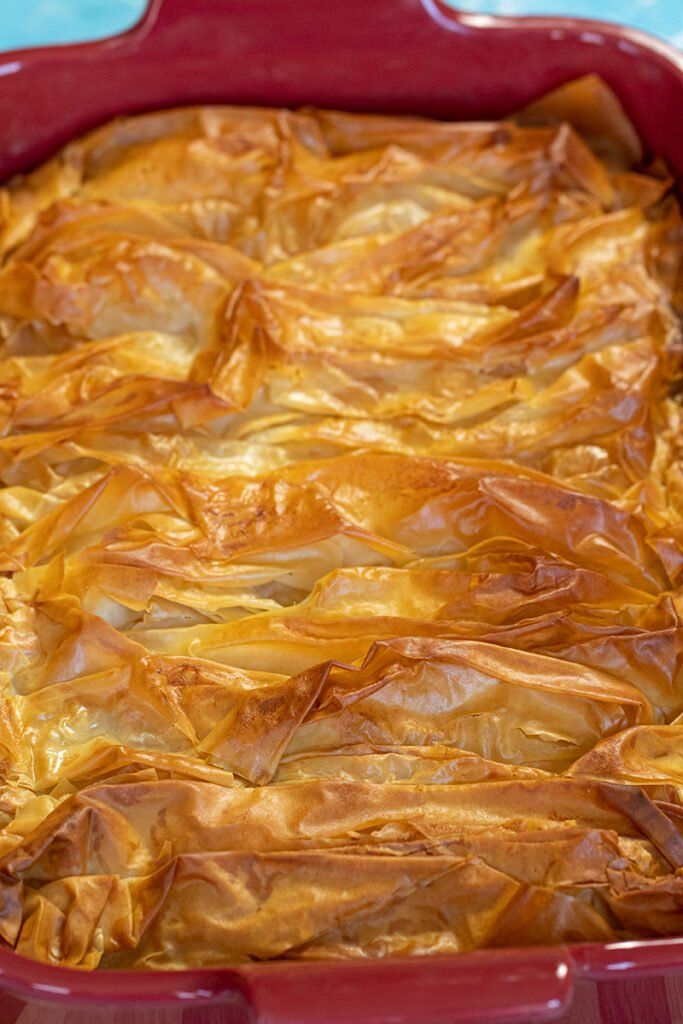 a red casserole dish filled with food on top of a blue table cloth