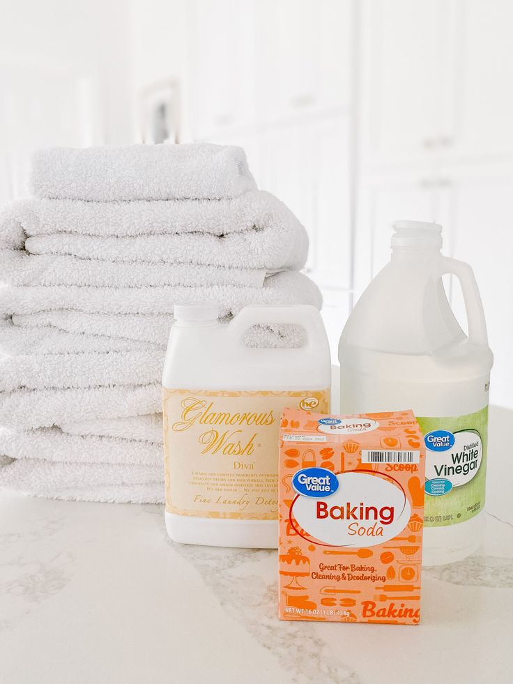 towels, detergent, and other cleaning products on a counter in front of a stack of folded white towels