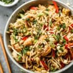 a bowl filled with noodles and vegetables next to chopsticks on a table top