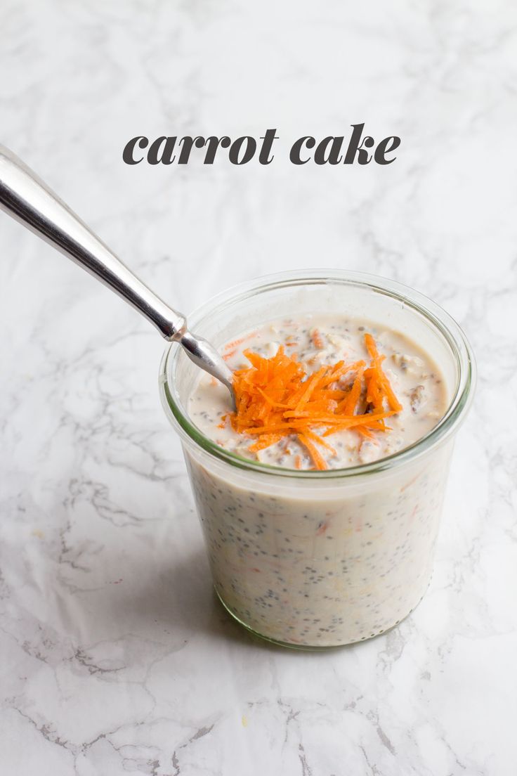 carrot cake in a small glass jar with a spoon sticking out of it on a marble surface