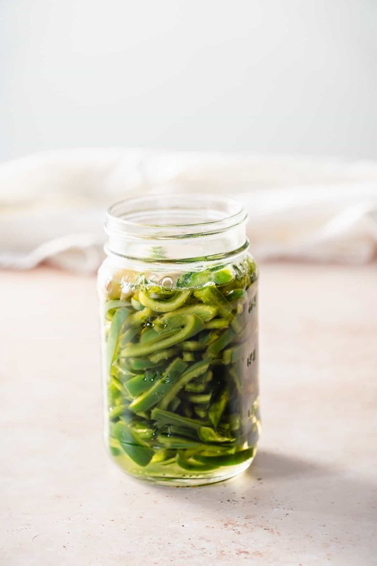 a jar filled with green beans sitting on top of a table