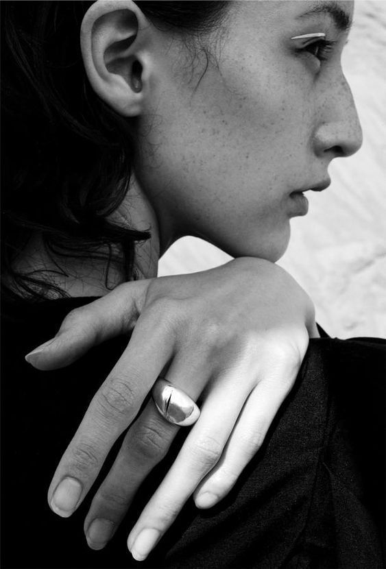 black and white photograph of a woman with her hand on her shoulder wearing a ring