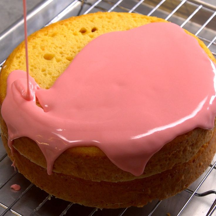 a cake with pink icing sitting on top of a cooling rack