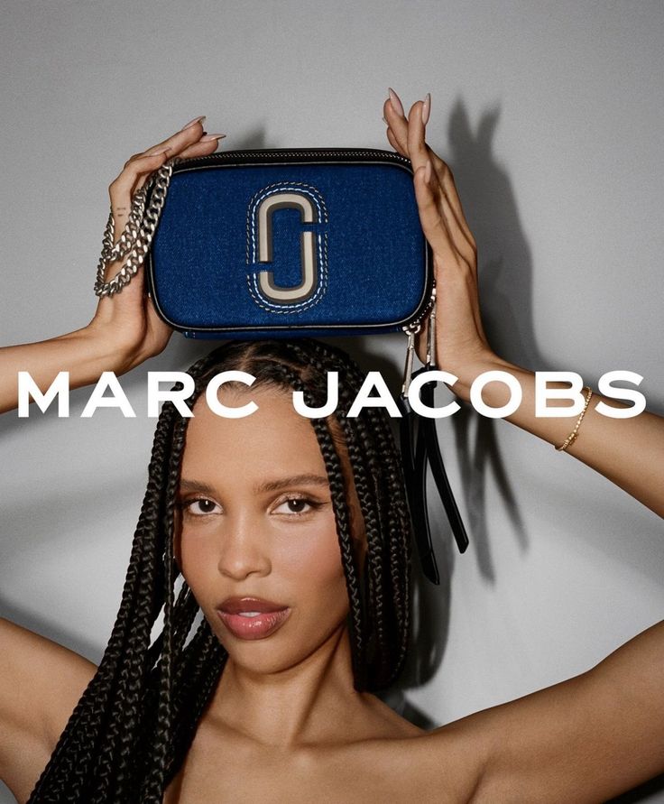 a woman holding up a blue purse over her head with the words marc jacobs on it