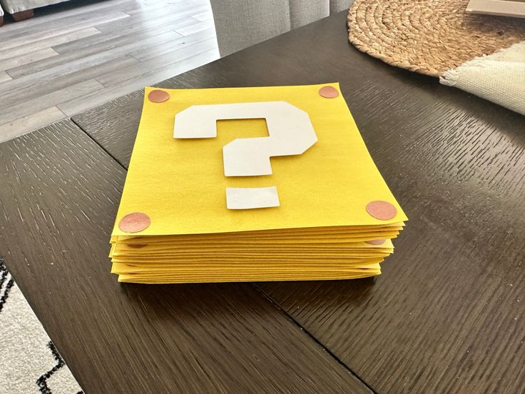 a stack of yellow paper with a question mark on it sitting on top of a wooden table