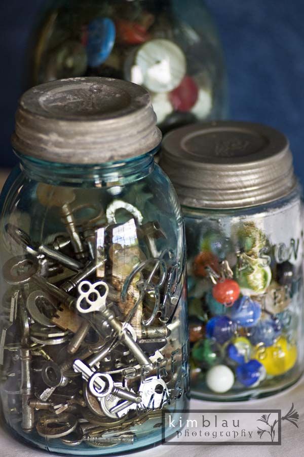 two mason jars filled with lots of different types of buttons and keys on top of a table