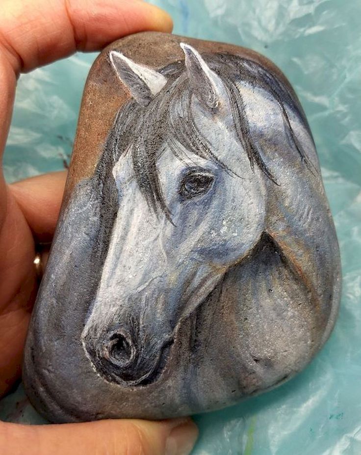 a hand holding a rock with a horse painted on it