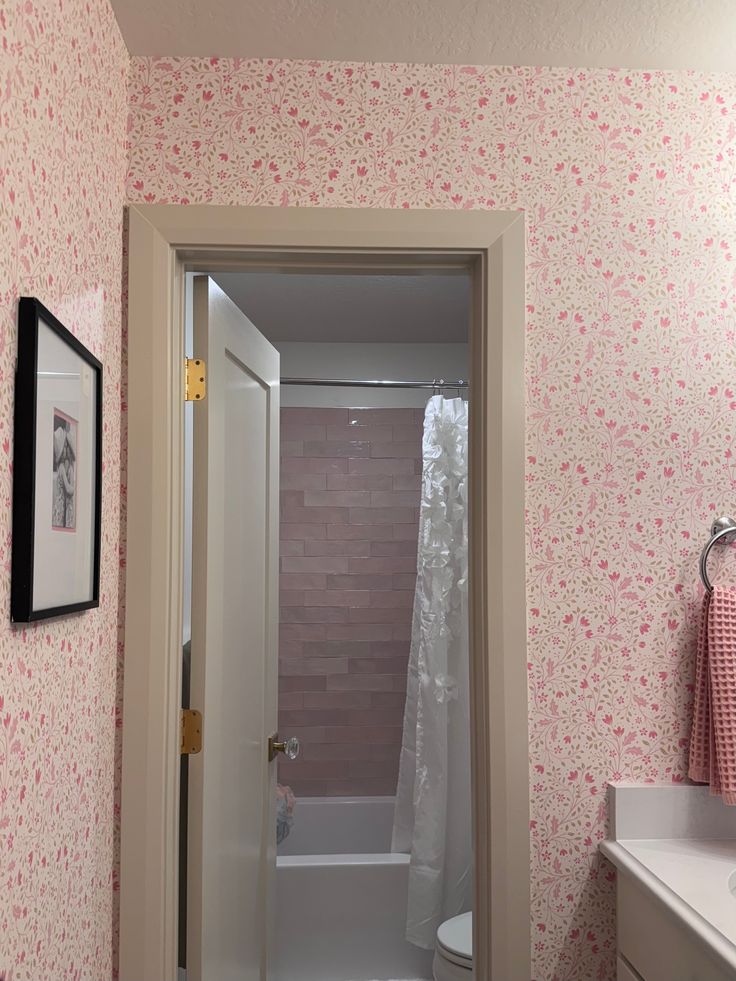 the bathroom is decorated in pink and white with floral wallpaper on the shower curtain