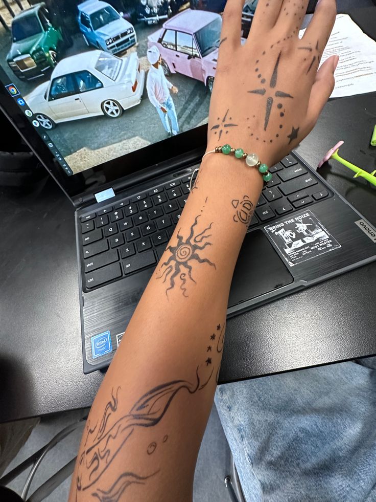 a person's arm with tattoos on it and a laptop in front of them