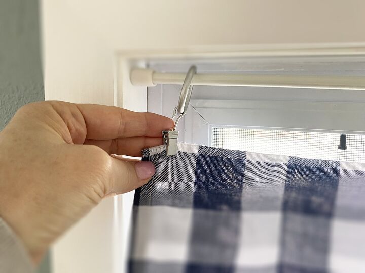 a person is cutting fabric with scissors on a window sill in front of a blue and white checkered curtain