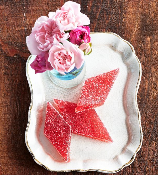 some pink flowers are in a vase and on a white plate with red glitter bow