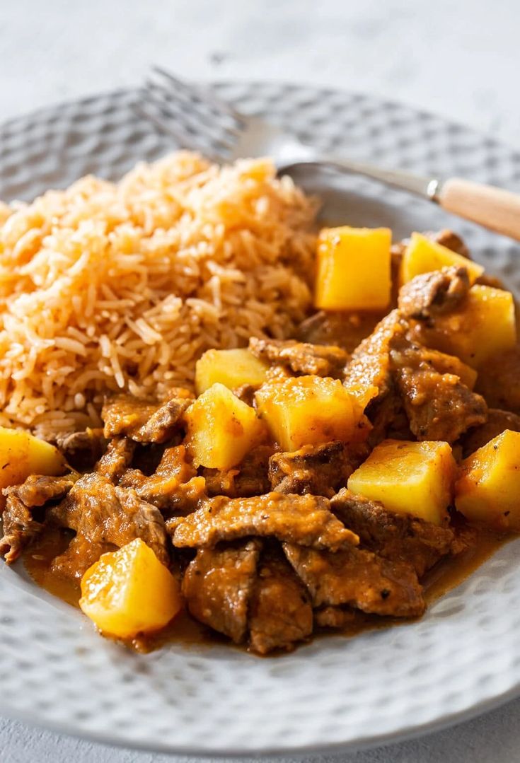 a white plate topped with meat and pineapple next to rice